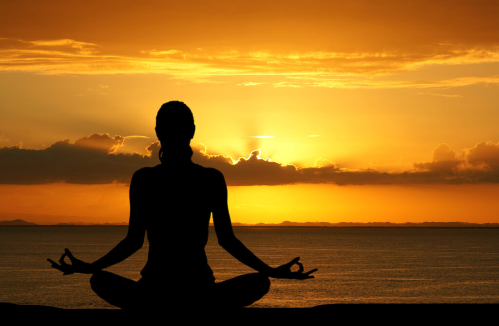 Woman working out doing yoga at the beach